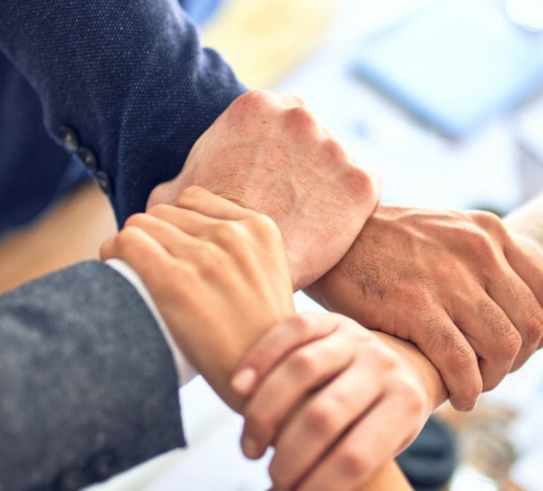 ¡Únete a Nosotros! Manos entrelazadas en un gesto de apoyo y colaboración.